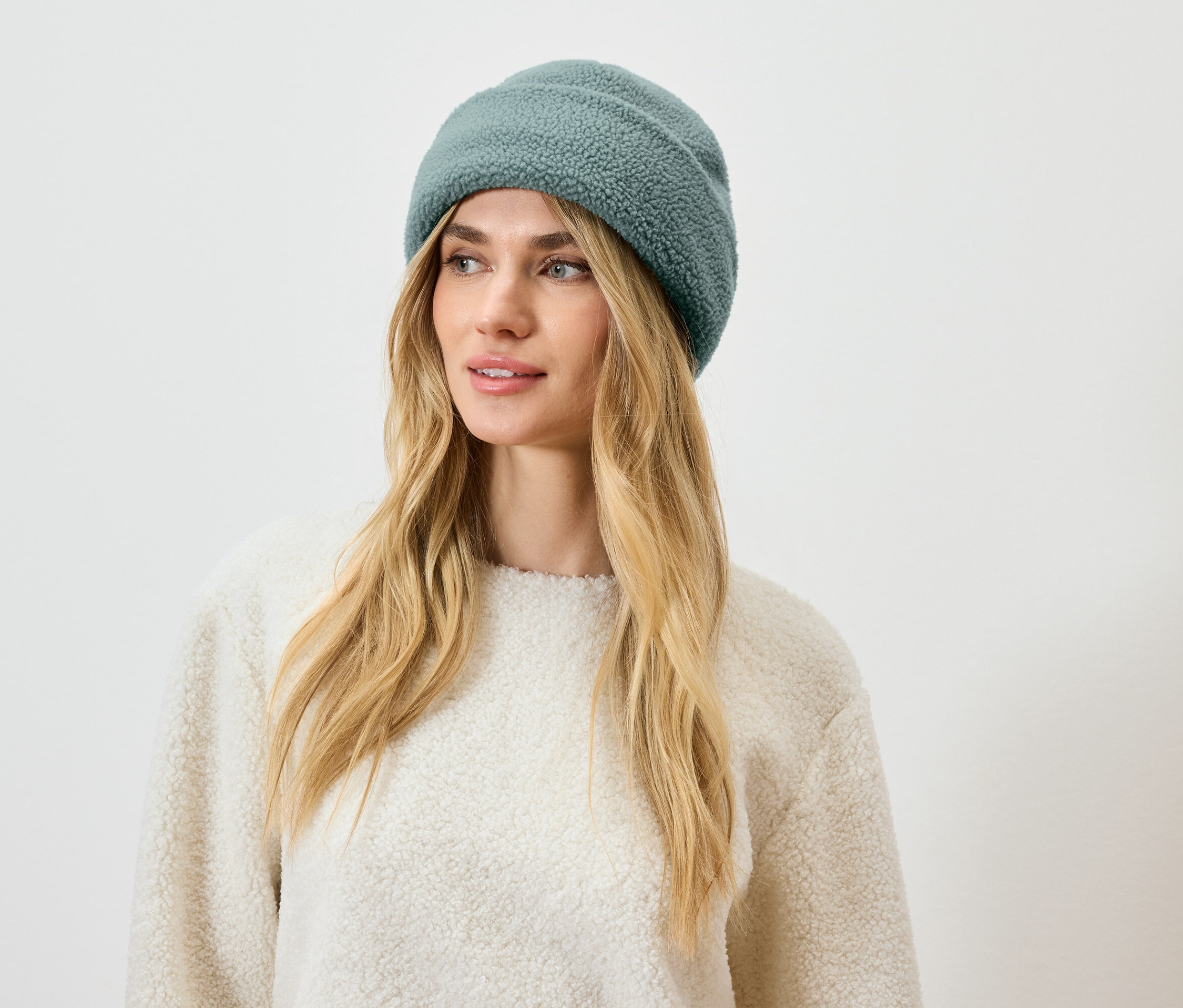 Blond hajú nő kékeszöld sapkában.