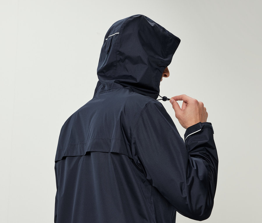 Férfi sötétkék kapucnis esőkabátban húzza meg a kapucni zsinórját.