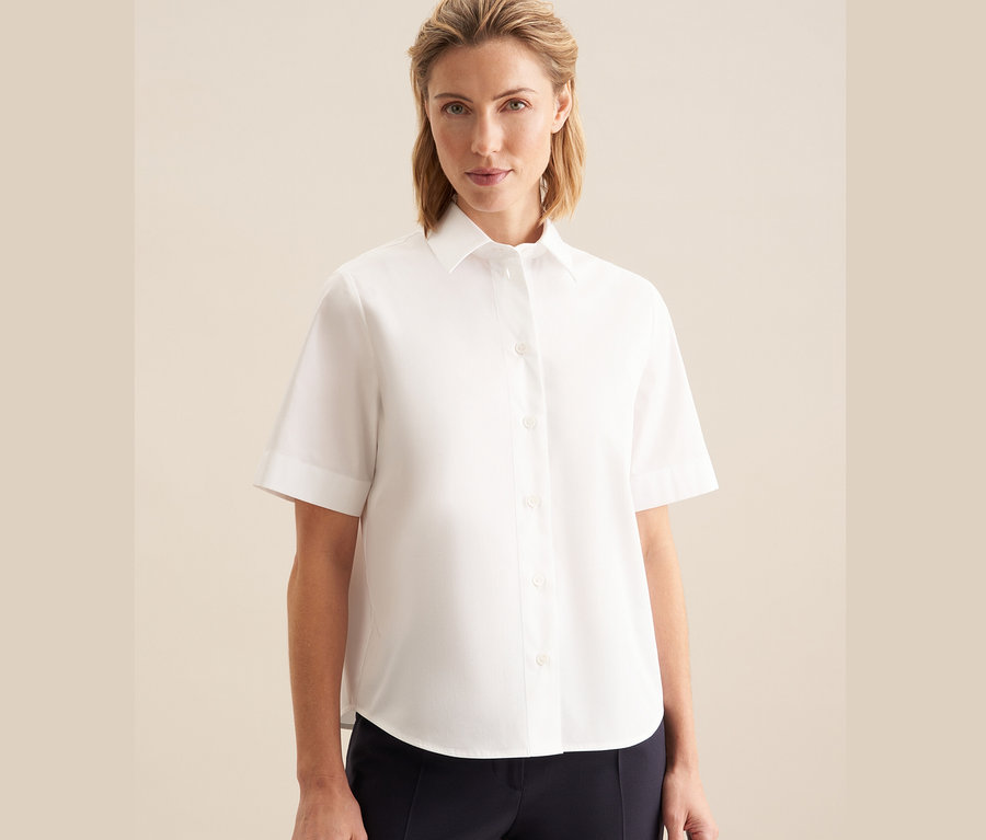Nő visel egy fehér Seidensticker rövid ujjú blúzt.