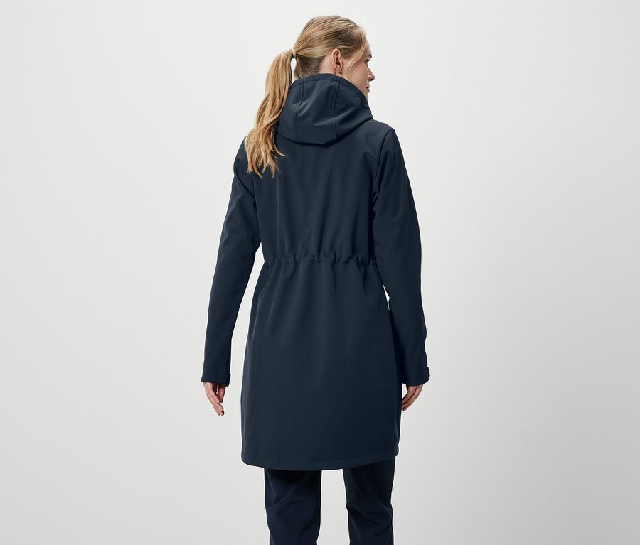 Hátulról látható egy szőke hajú, lófarokba kötött nő, sötétkék kabátot és nadrágot visel.