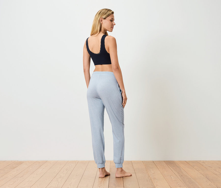 Hátulról látható nő fekete sportmelltartót és világoskék jogging nadrágot visel.