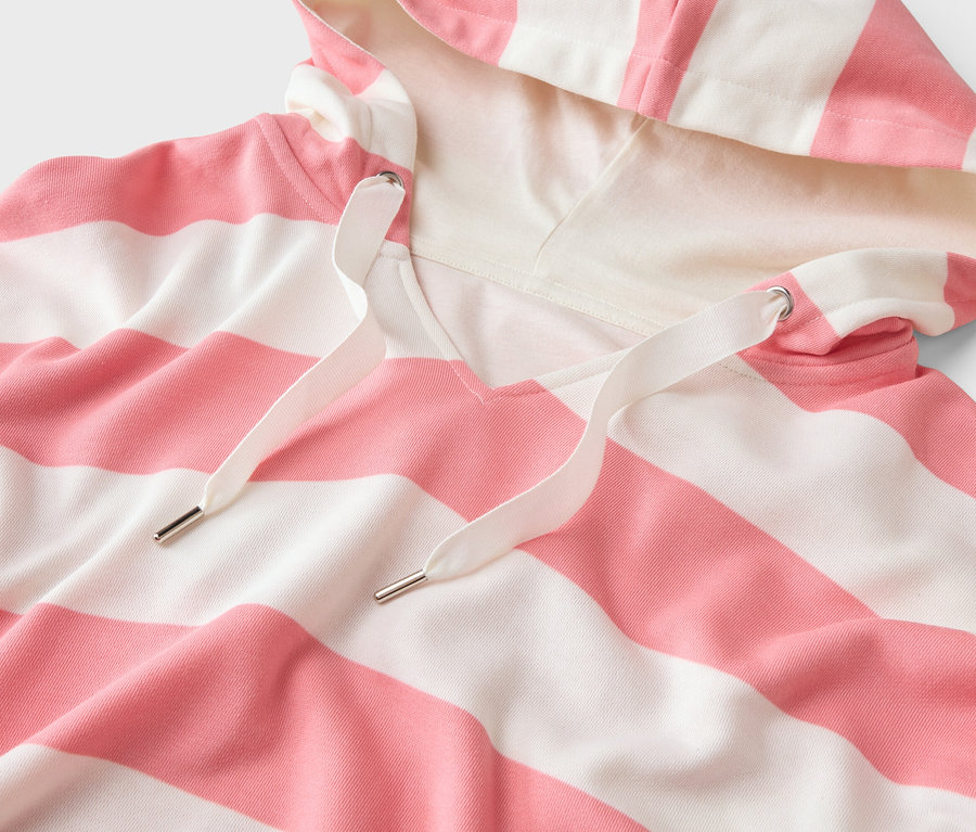 Egy rózsaszín-fehér csíkos kapucnis pulóver közeli képe, húzózsinórral.