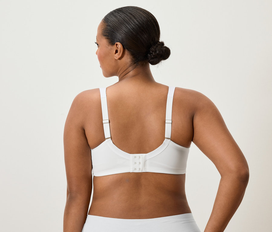 Hátulnézet egy kontyos hajú nőről, aki fehér melltartót és alsóneműt visel.