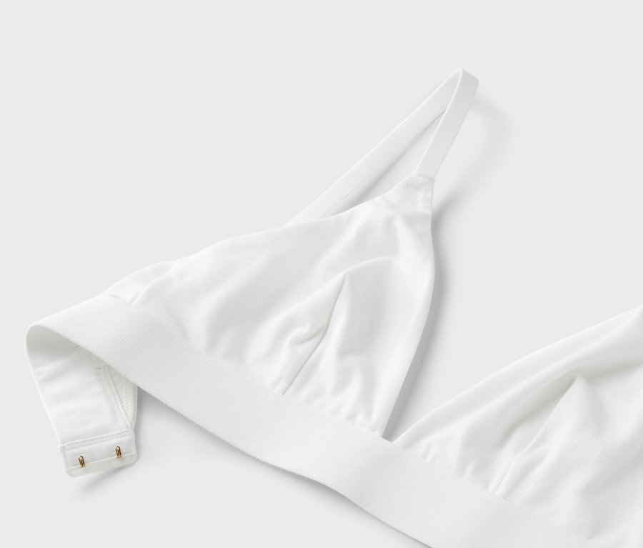 Közeli kép egy fehér, vékony pántos melltartóról fehér háttérrel.