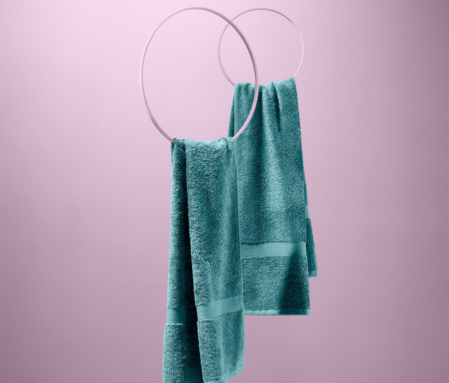Két türkiz frottír törölköző, 2 törölköző szettben, fehér karikákon lógnak rózsaszín háttér előtt.