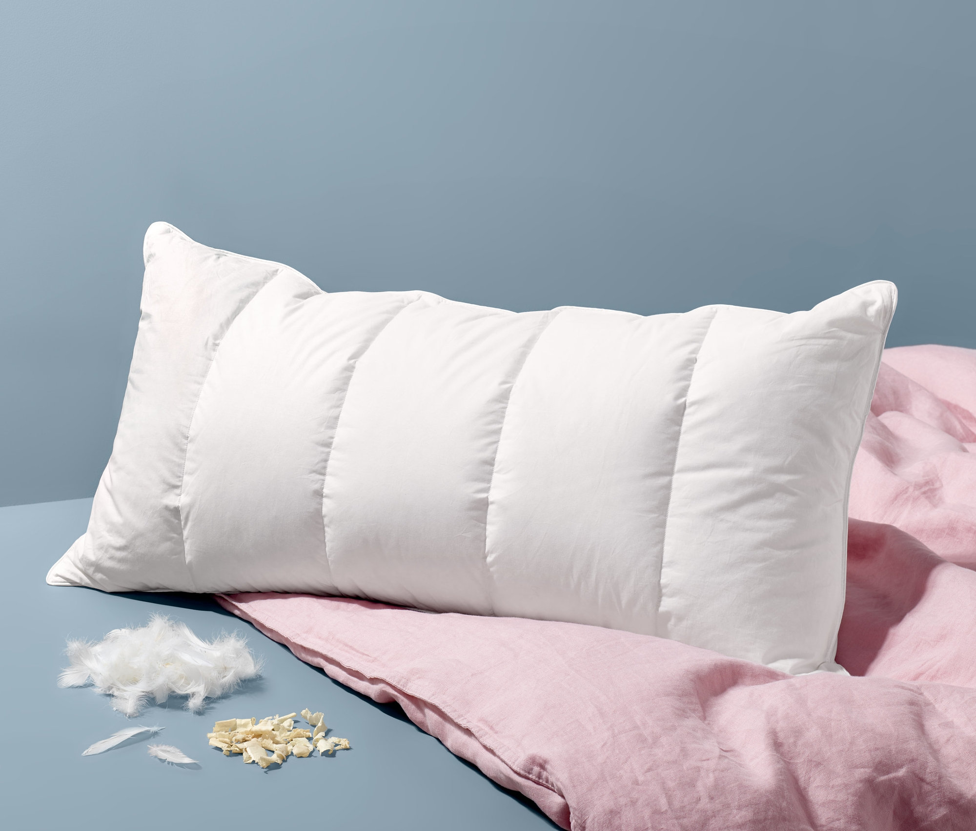 Egy fehér, steppelt Cirbolyafenyő párna fekszik egy rózsaszín vászon ágyneműn.