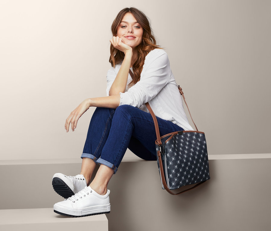 Nő ül a lépcsőn, és oldaltáskát visel.