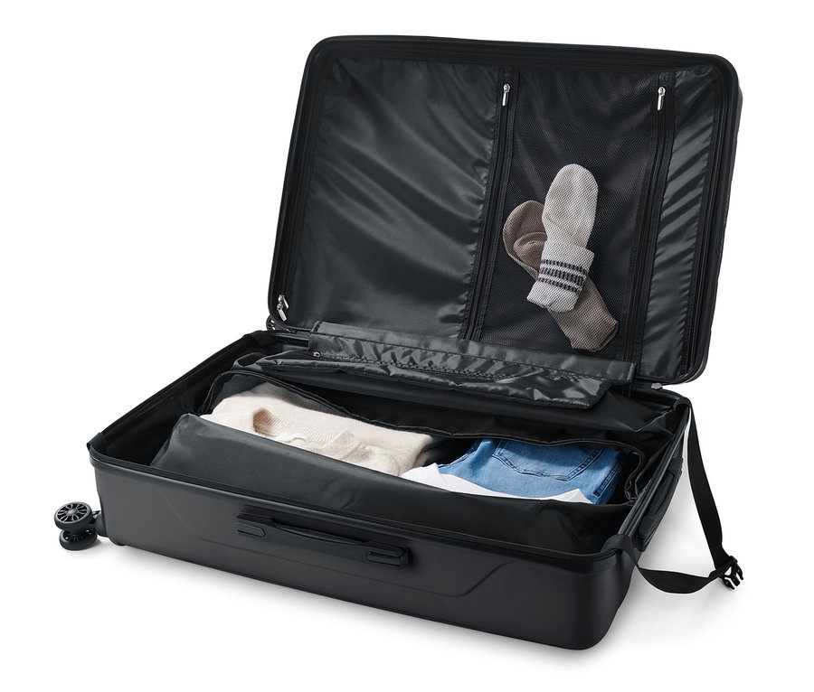 Egy nagy, kemény bőrönd nyitva, benne ruhákkal.