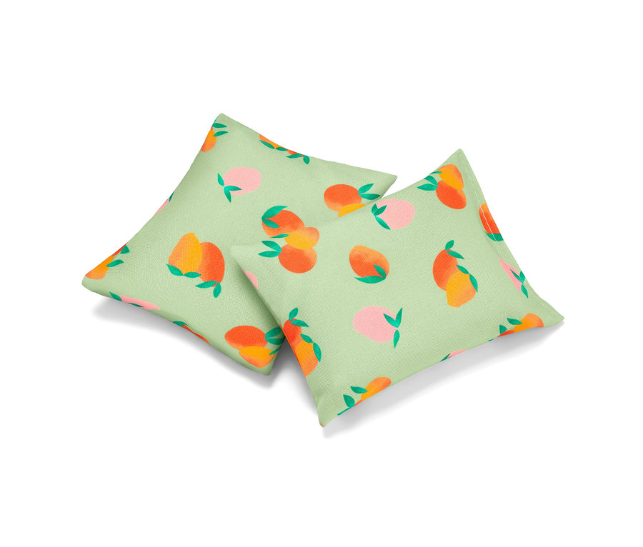 Két frissítő párna barackmintával, világoszöld háttérrel.