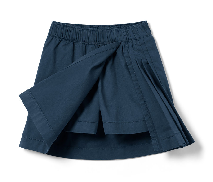 Egy sötétkék, pliszírozott kisgyerek skót szoknya közeli képe.