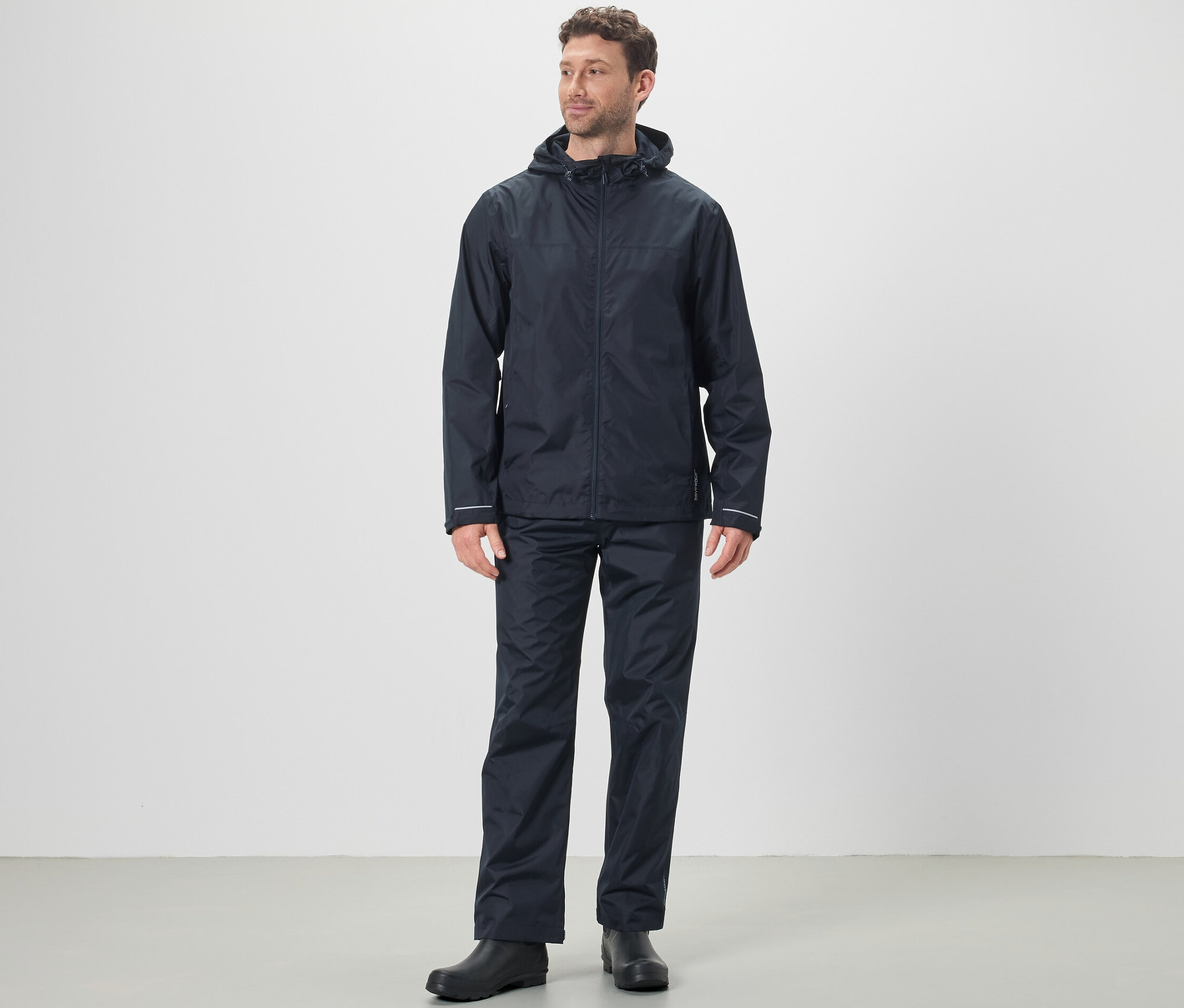 Egy férfi esőkabátot és unisex esőnadrágot visel.