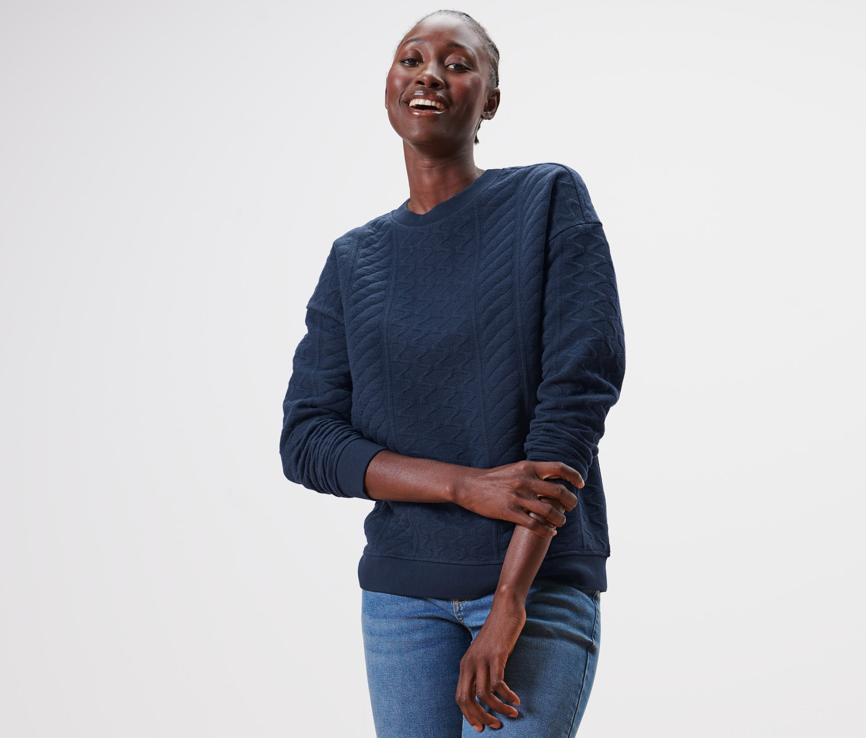 Nő visel egy sötétkék, strukturált szabadidőfelsőt és farmert.