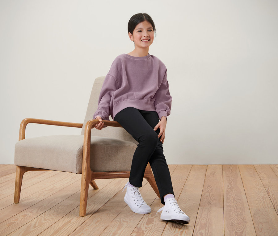 Lány ül a széken, fekete gyerek termoleggingsben.