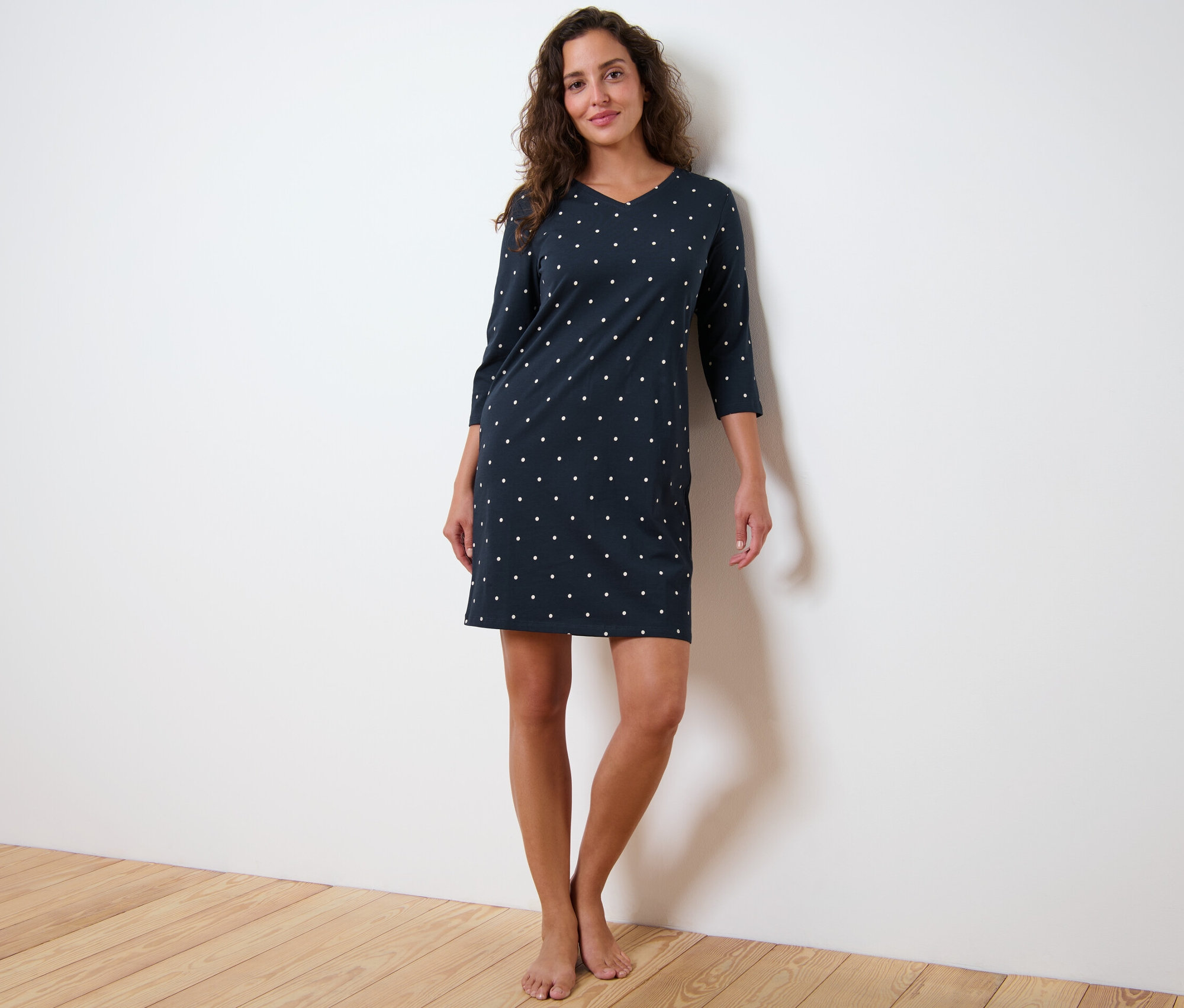 Nő áll pöttyös, háromnegyedes ujjú hálóingben.