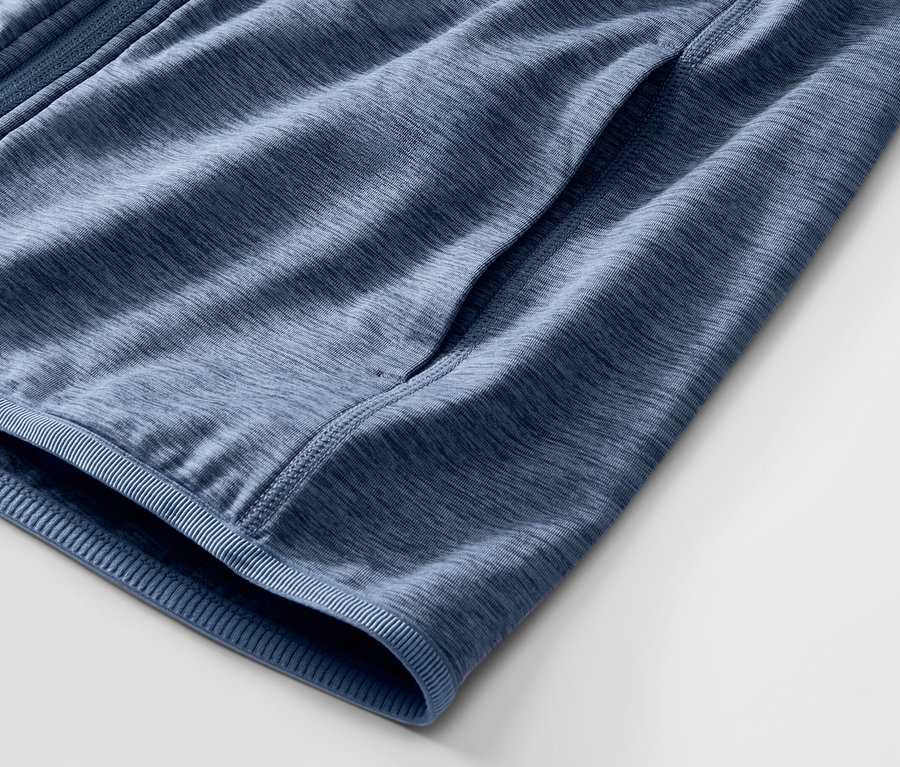 Egy melírozott kék női sportfelső részlete, zsebbel.