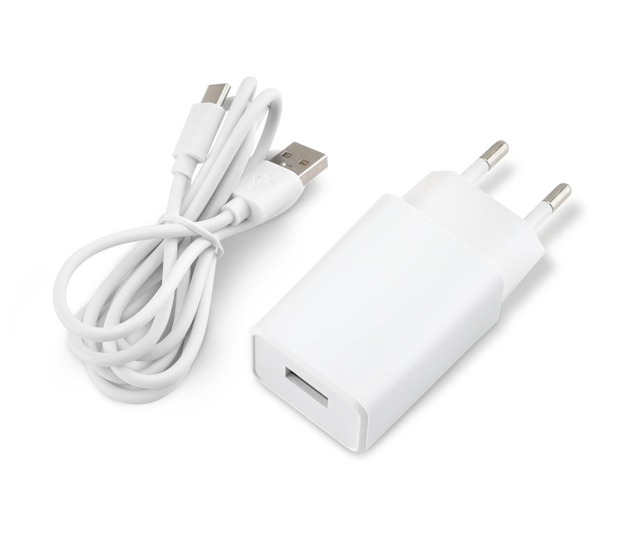 Egy fehér adapter és egy feltekert USB-kábel fekszik egy fehér felületen.