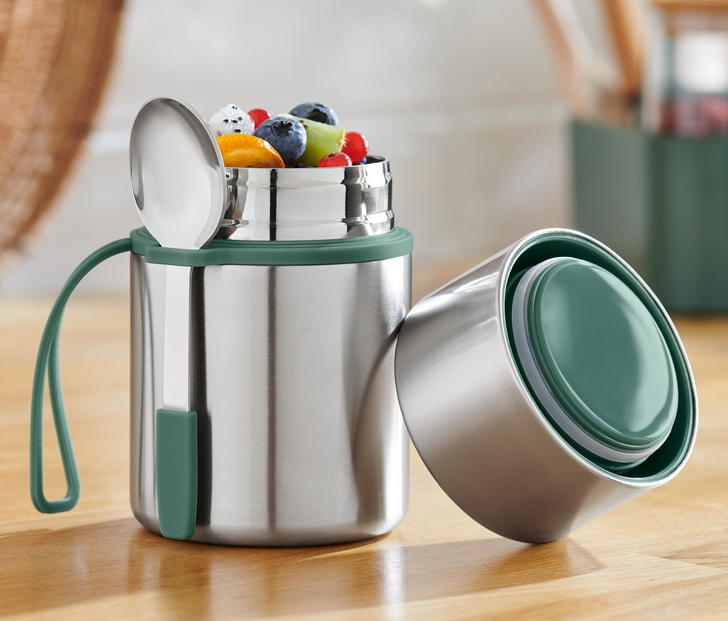 Nyitott Ételhordó termosz gyümölcsökkel és kanállal egy fa asztalon.