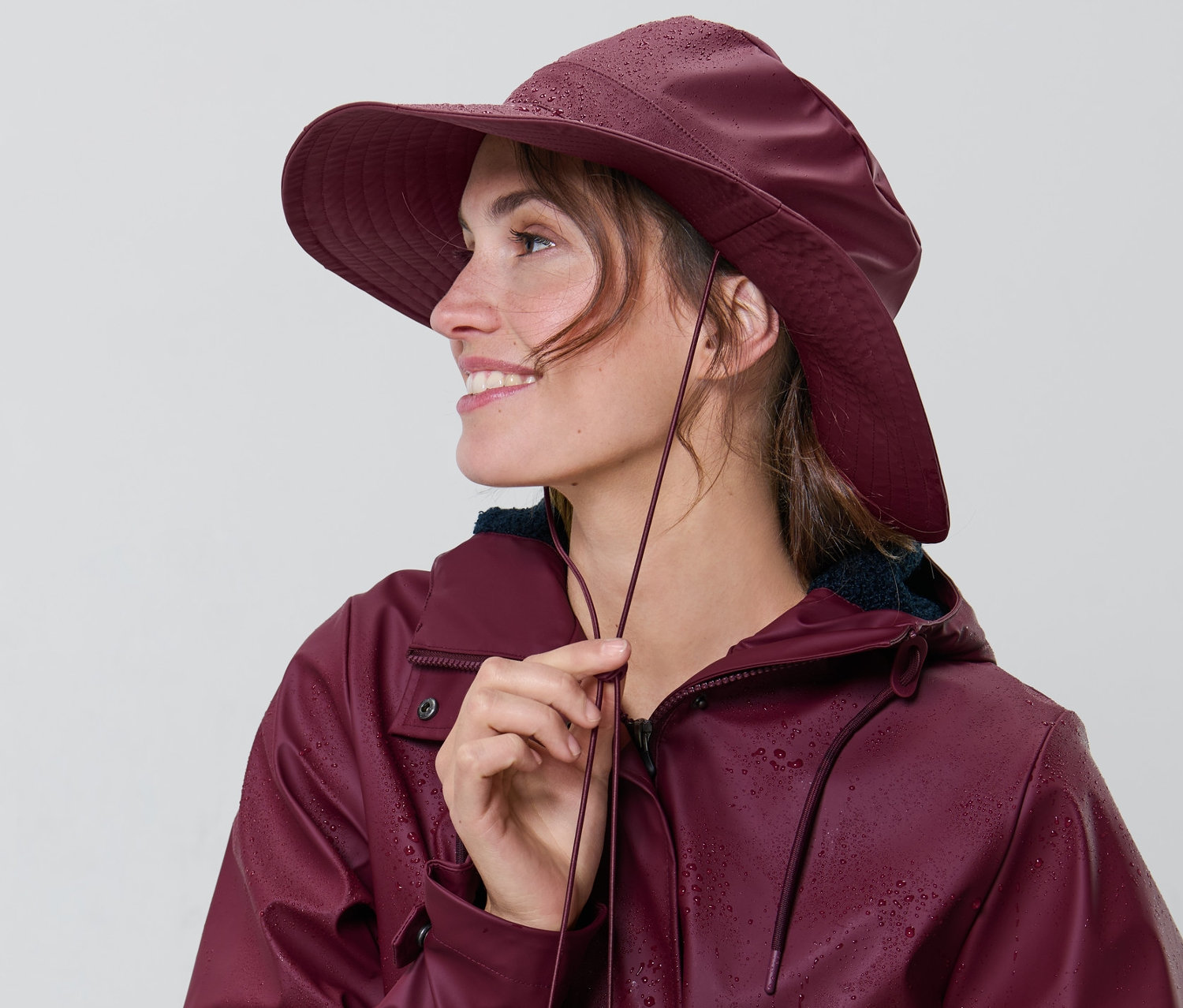 Nő állítja a zsinórt a bordó esőkalapján.