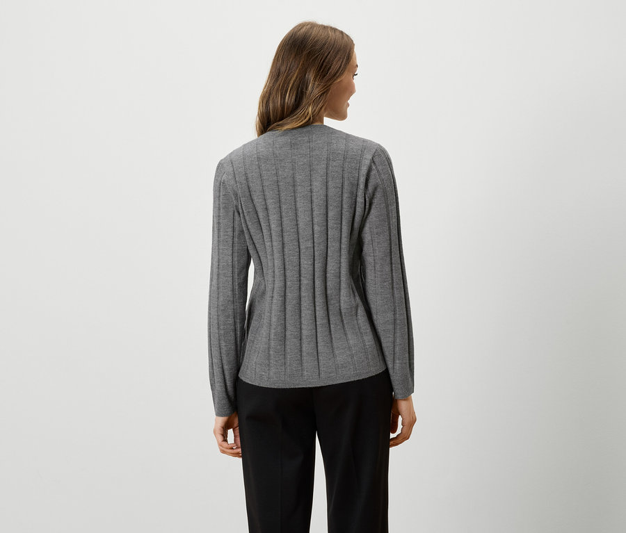 Egy nő hátulról látható, szürke, hosszú ujjú felsőben és fekete nadrágban.