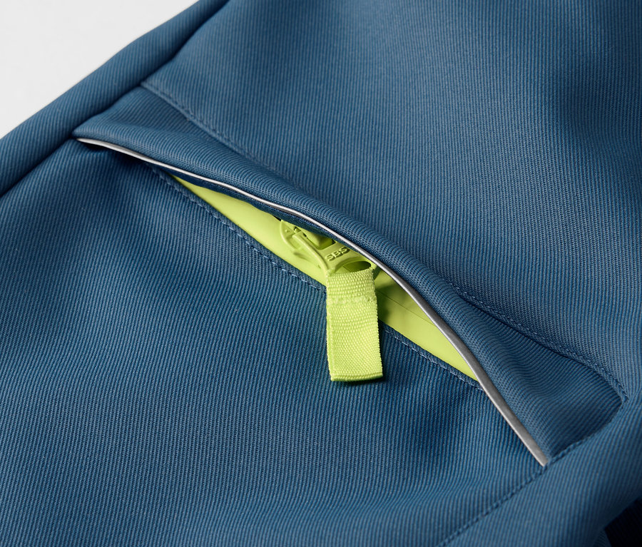 Egy gyermek softshell nadrág részlete neon zöld cipzárral.