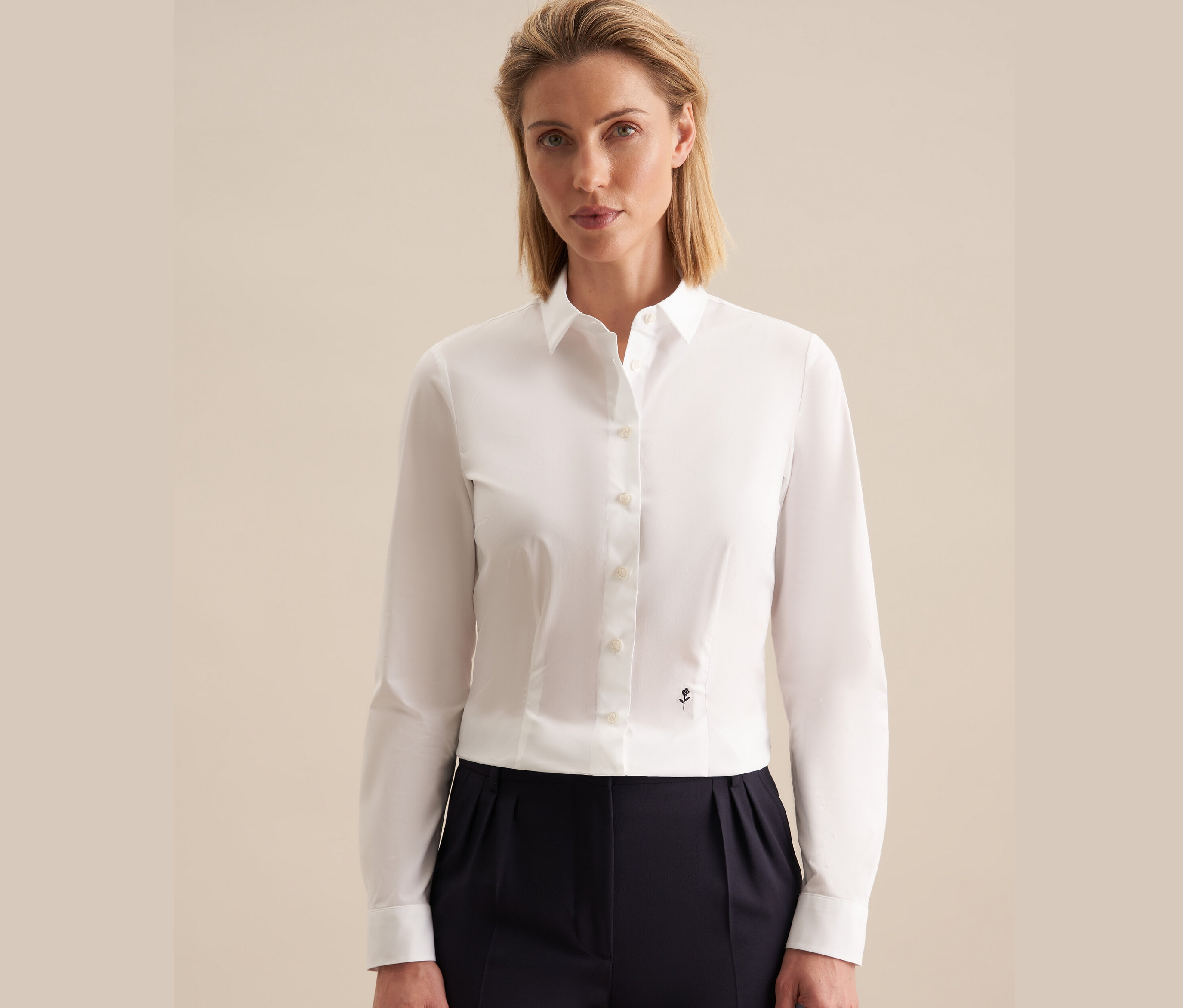 Nő visel egy fehér Seidensticker slimfit blúzt és egy sötétkék nadrágot.