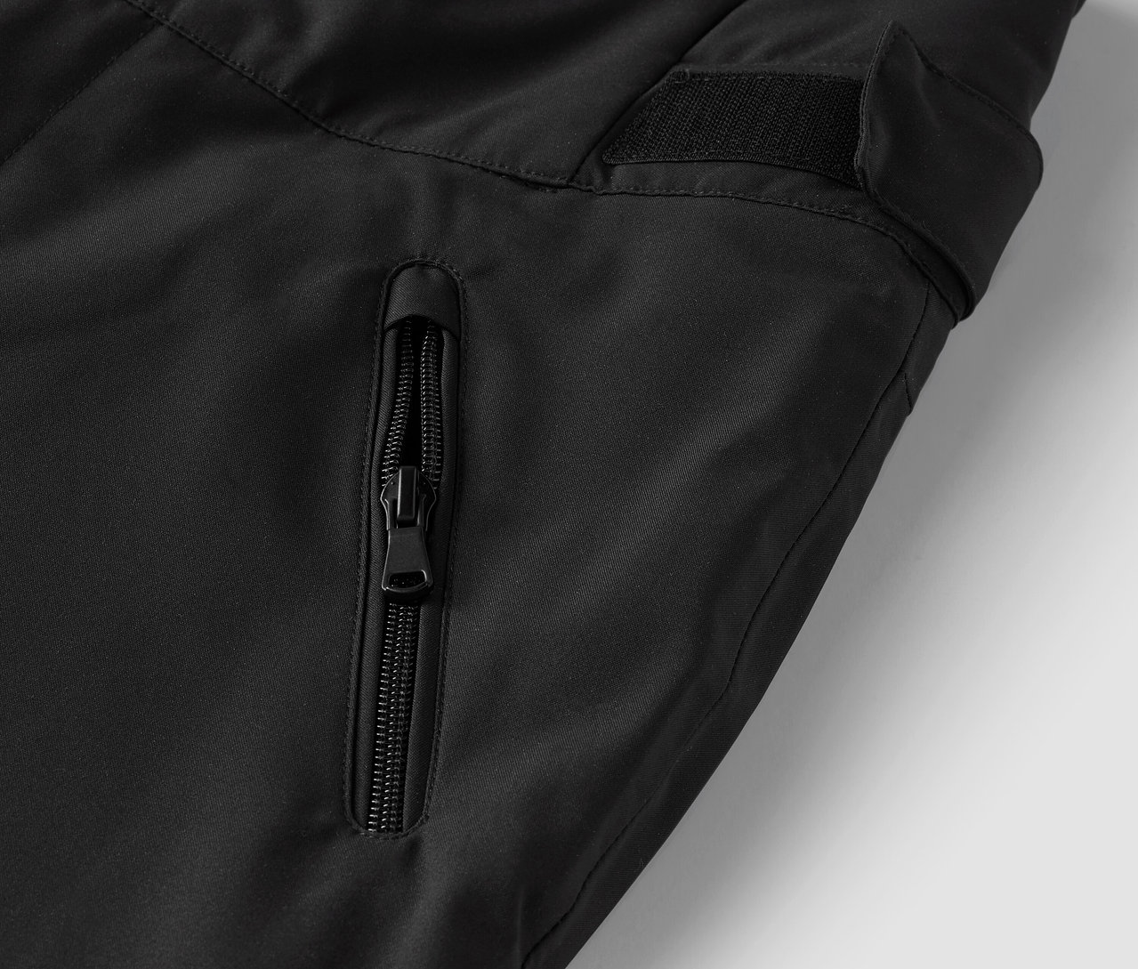 Egy fekete nadrág részlete cipzáras zsebbel.