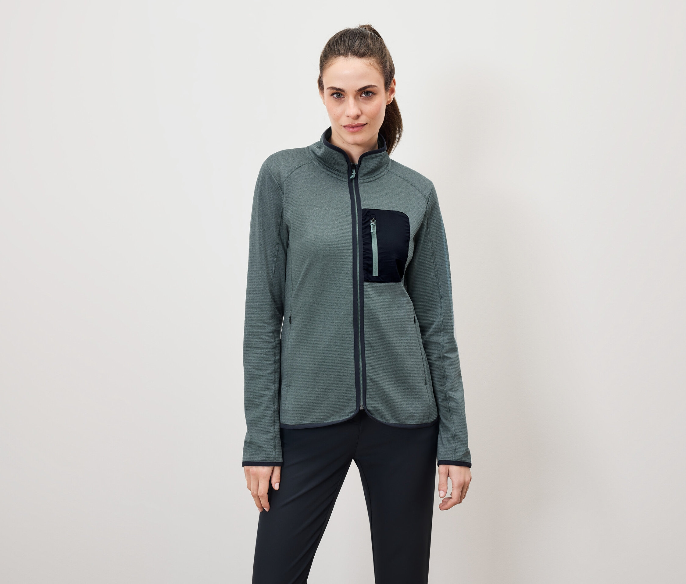 Nő visel zöld polár pulóvert fekete nadrággal.