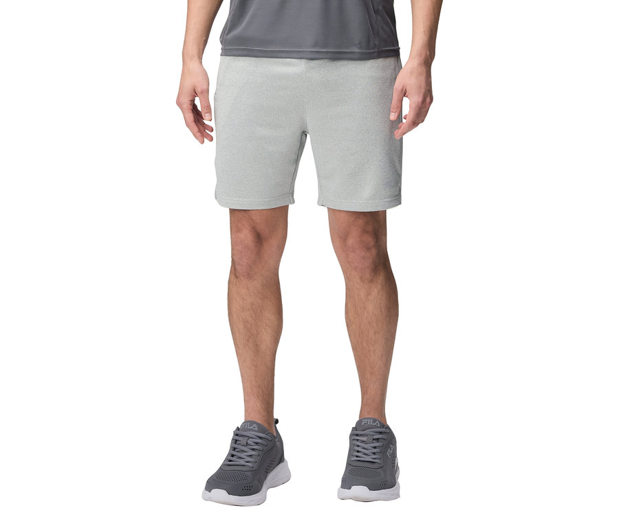 Férfi szürke rövidnadrágot és szürke Fila sportcipőt visel.