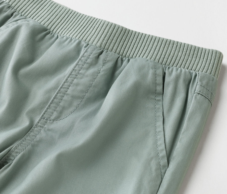 Közelkép egy világoszöld nadrágról, gumis derékrésszel.