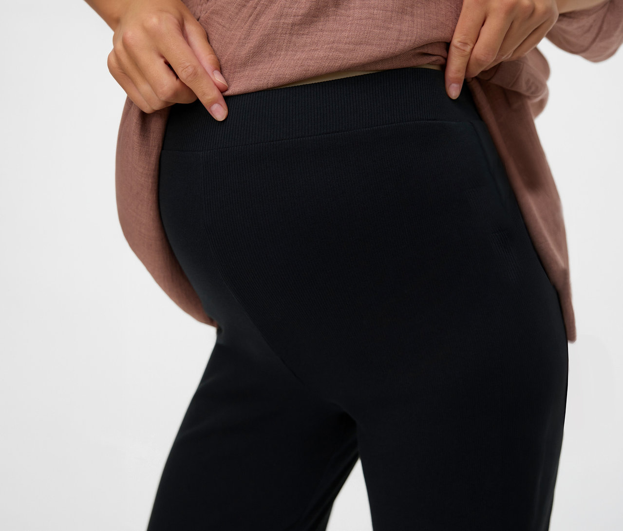Nő mutatja a MAMALICIOUS fekete, laza »MLEMILY« leggings derekát.