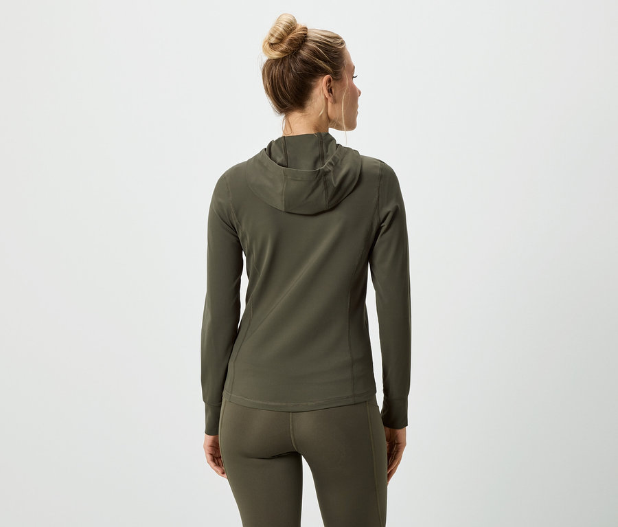 Hátulnézet egy kontyos hajú nőről, aki olívazöld kapucnis pulóvert és leggingst visel.