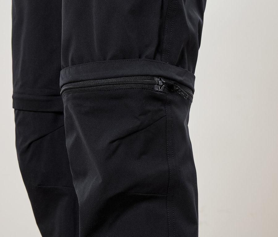 Egy fekete nadrág alsó részének közeli képe, cipzárral a száron.