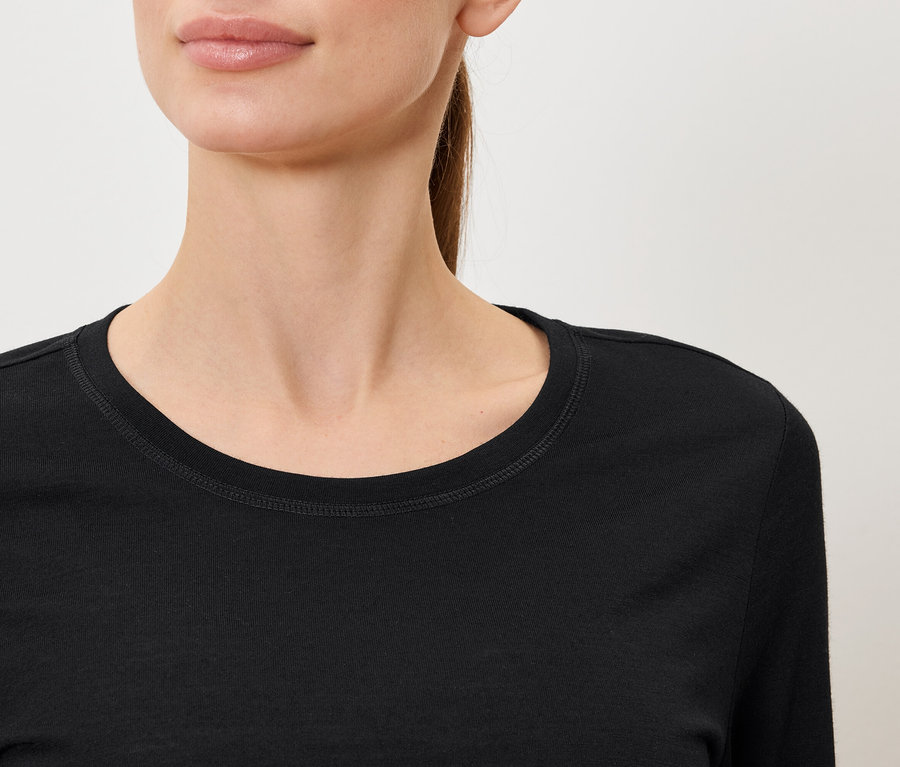 Egy fekete, hosszú ujjú pólót viselő nő közeli képe.