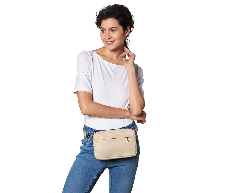 Nő pózol egy bézs biztonsági oldal- és övtáskával.