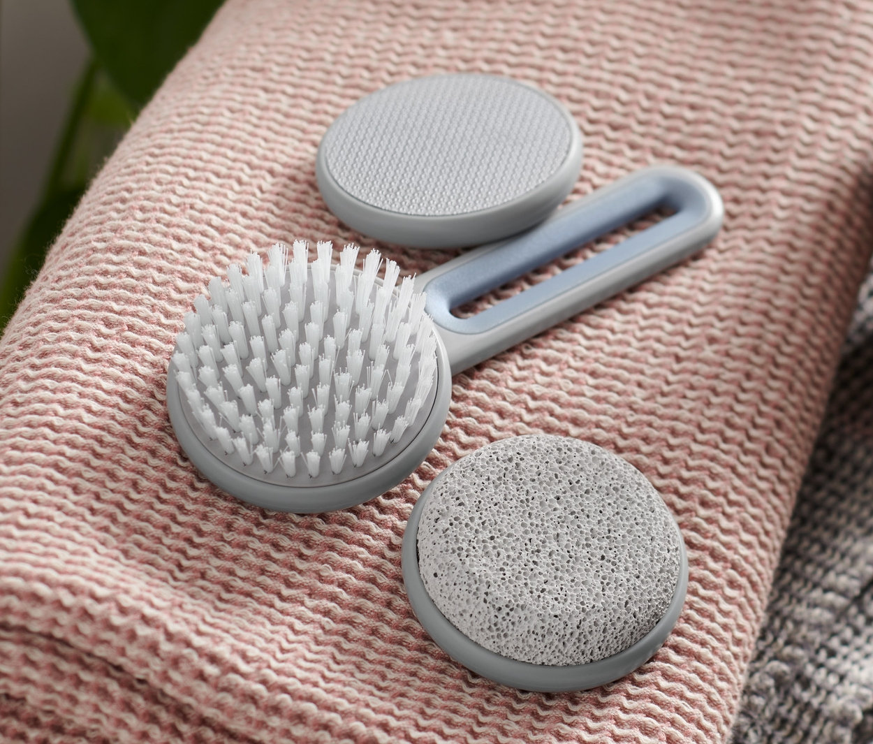 Lábápoló készlet egy rózsaszín törölközőn, egy barna pumpás üveg mellett.