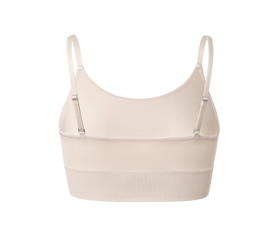Közeli kép egy bézs színű, varrás nélküli, állítható pántokkal rendelkező crop top hátulról.