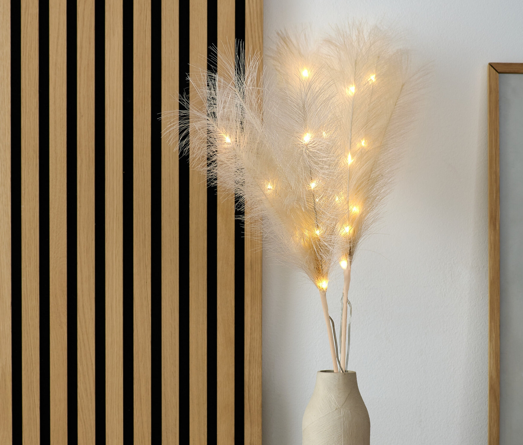 LED-es pampafű dekor ág vázában a komódon.