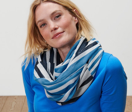 Szőke nő ül a földön, és csíkos csősálat visel.