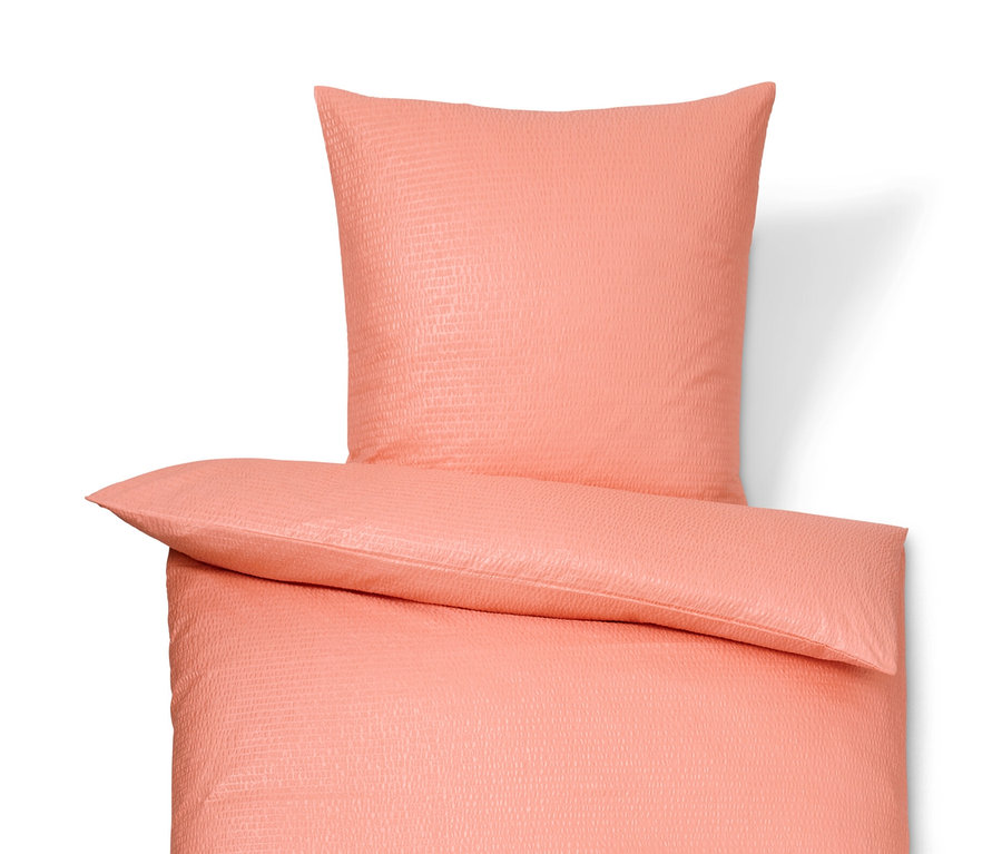 Korall színű, normál és extra méretű krepp ágynemű fehér háttéren.