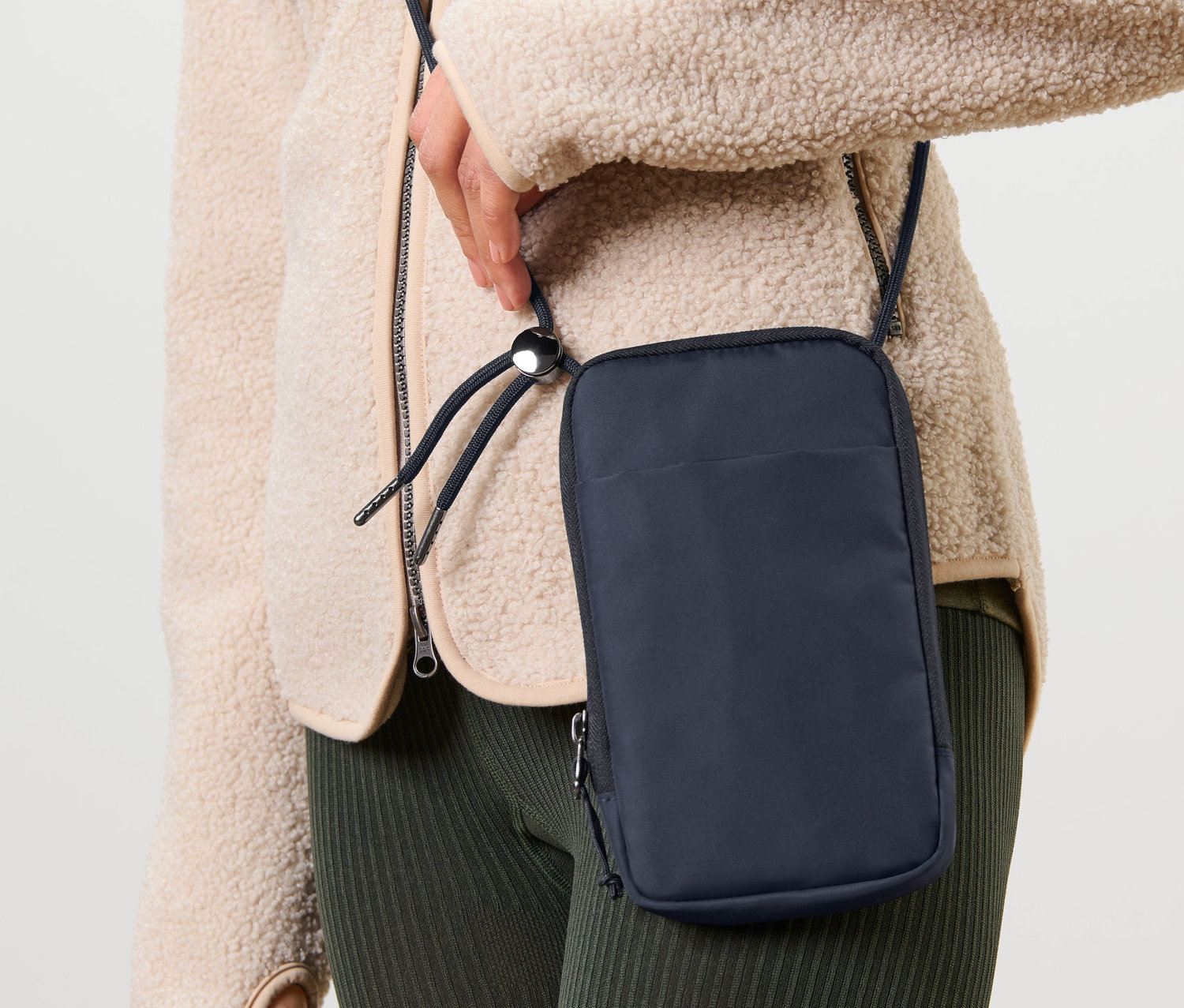 Nő visel egy sötétkék fagyálló okostelefon-táskát a vállán.