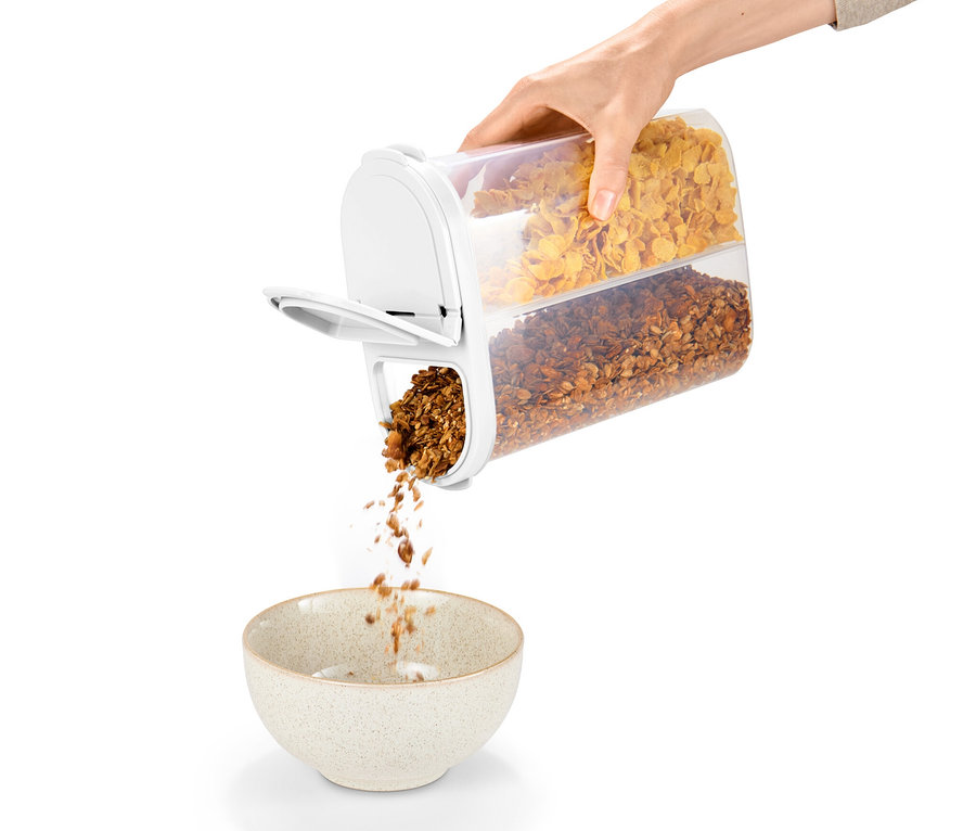 Egy kéz egy 2 az 1-ben tárolódobozból granolát önt egy tálba.