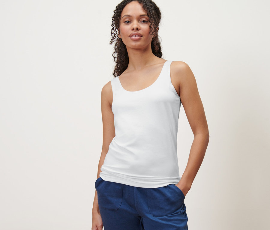 Nő pózol fehér trikóban. 2 női trikó, fekete/fehér.