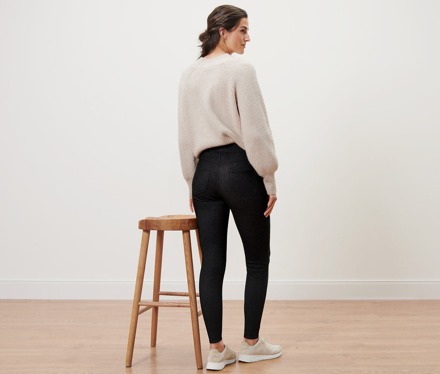 Hátulról látható nő farmer hatású bélelt leggingsben és pulóverben.