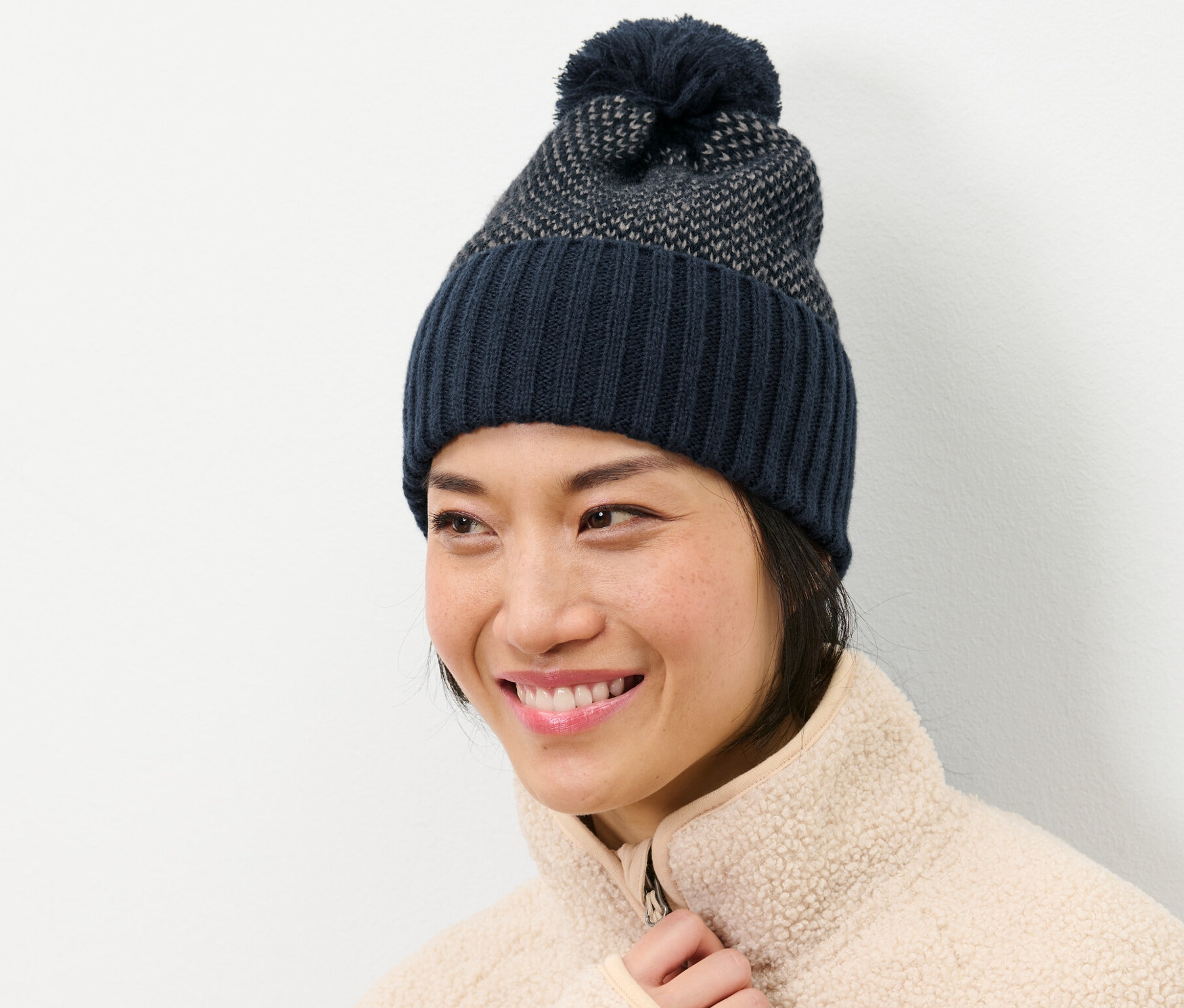 Mosolygó nő kötött sapkát visel.