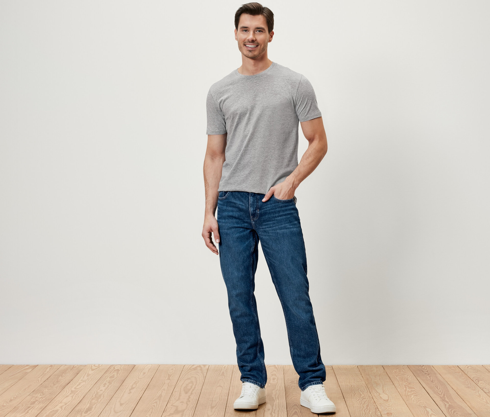 Egy férfi áll és sötétkék férfi farmernadrágot visel.