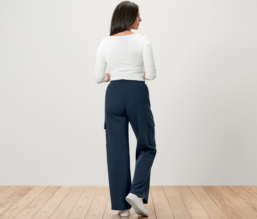 Hátulról látható nő sötétkék szabadidőnadrágot visel oldalzsebekkel.
