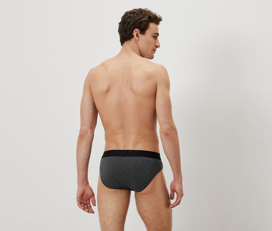 Egy férfi háttal a kamerának szürke alsónadrágot visel.