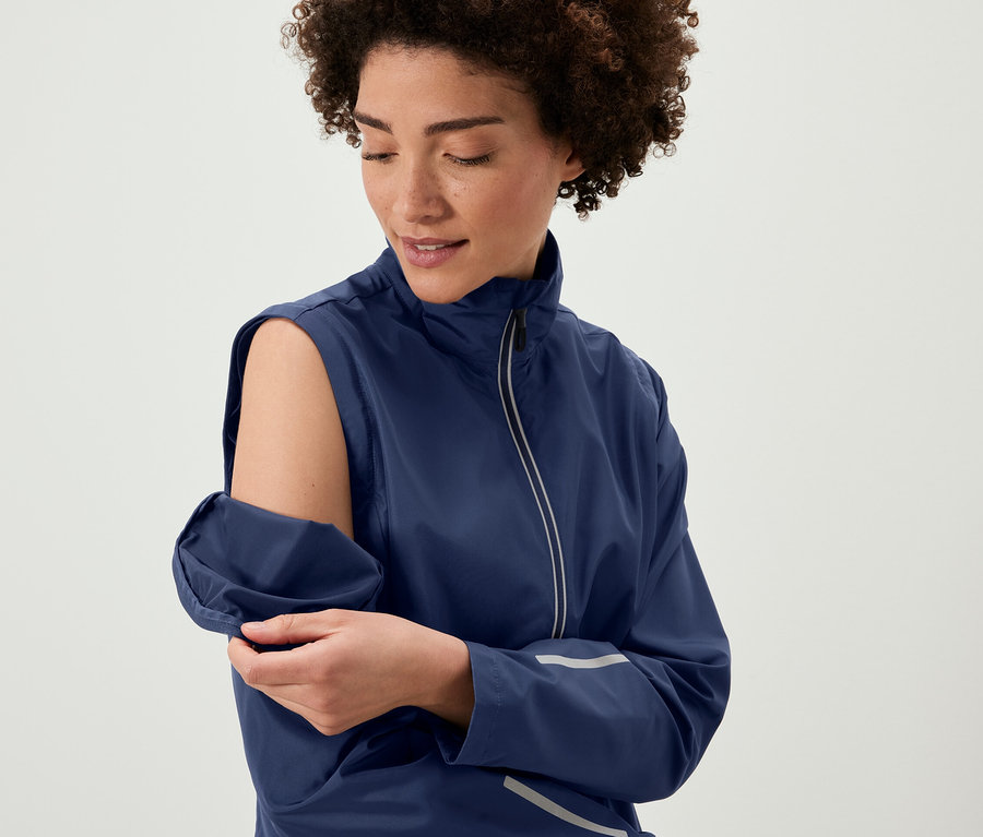 Nő levehető ujjakat visel egy 2 az 1-ben kerékpáros kabáton.