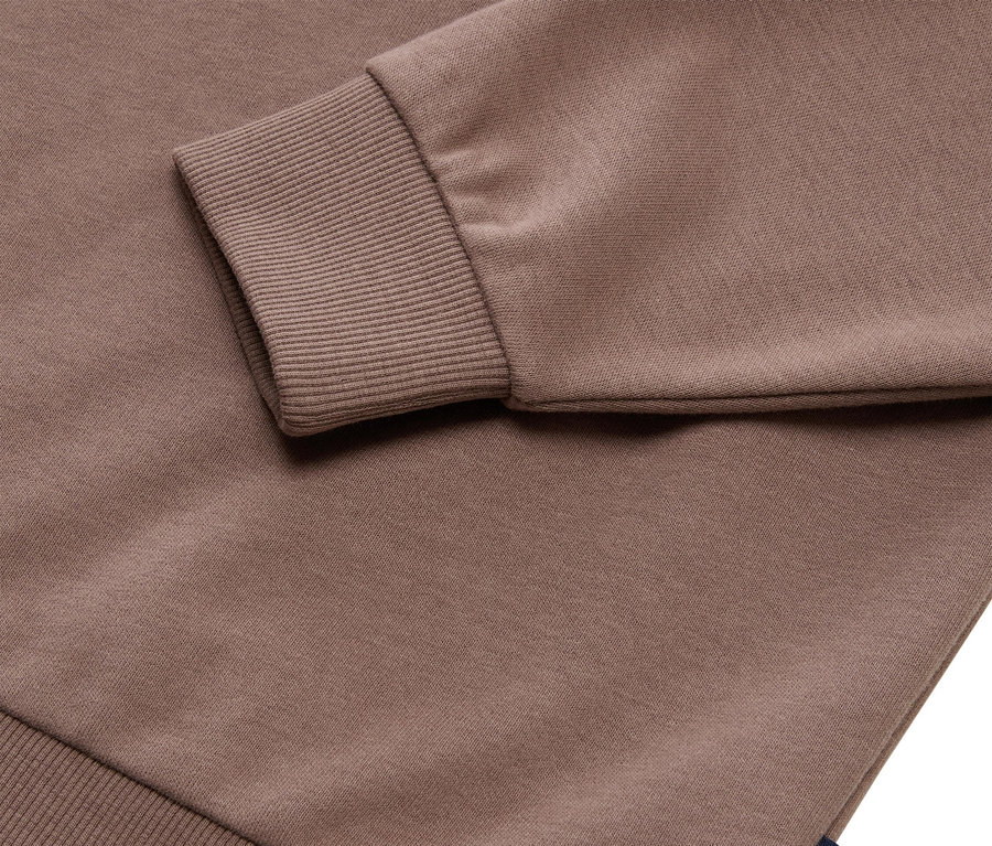 Közelkép egy barna Tom Tailor pulóverről bordázott mandzsettával.