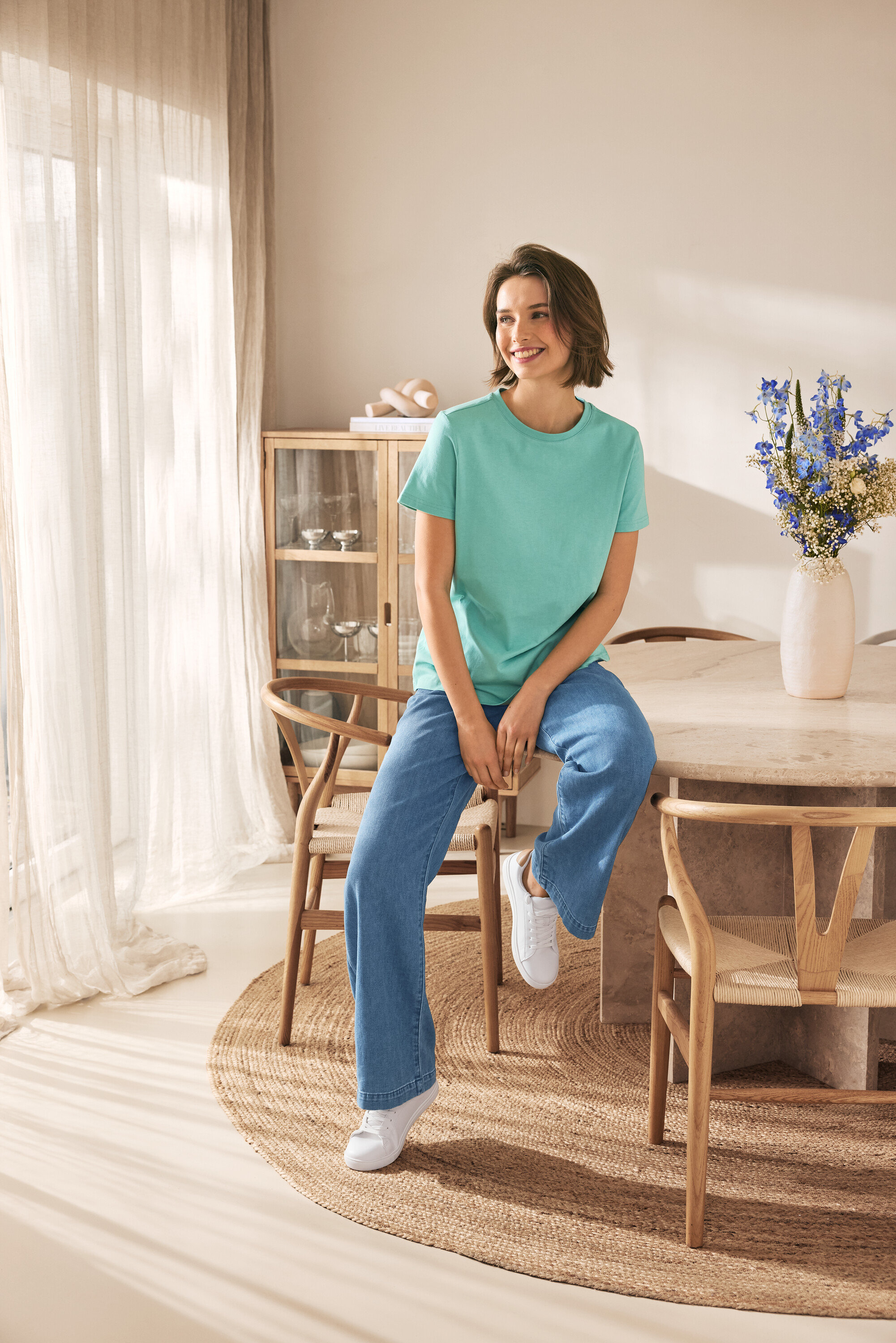 Nő ül egy széken és bőr sneakert visel.